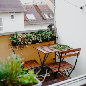 la table est installée sur un balcon, conte un muret, et les deux chaises sont légèrement tirée pour permettre à une personne de s'assoire